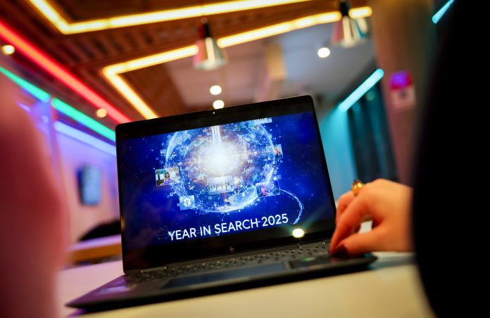 Zwei Google-Mitarbeiterinnen zeigen auf einem Laptop das Startbild einer Präsentation zur Vorstellung der Google-Suchtrends des Jahres 2025 in der Zukunftswerkstatt im deutschen Hauptsitz von Google.