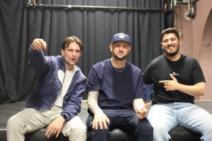 Drei Männer sitzen auf der Bühne.