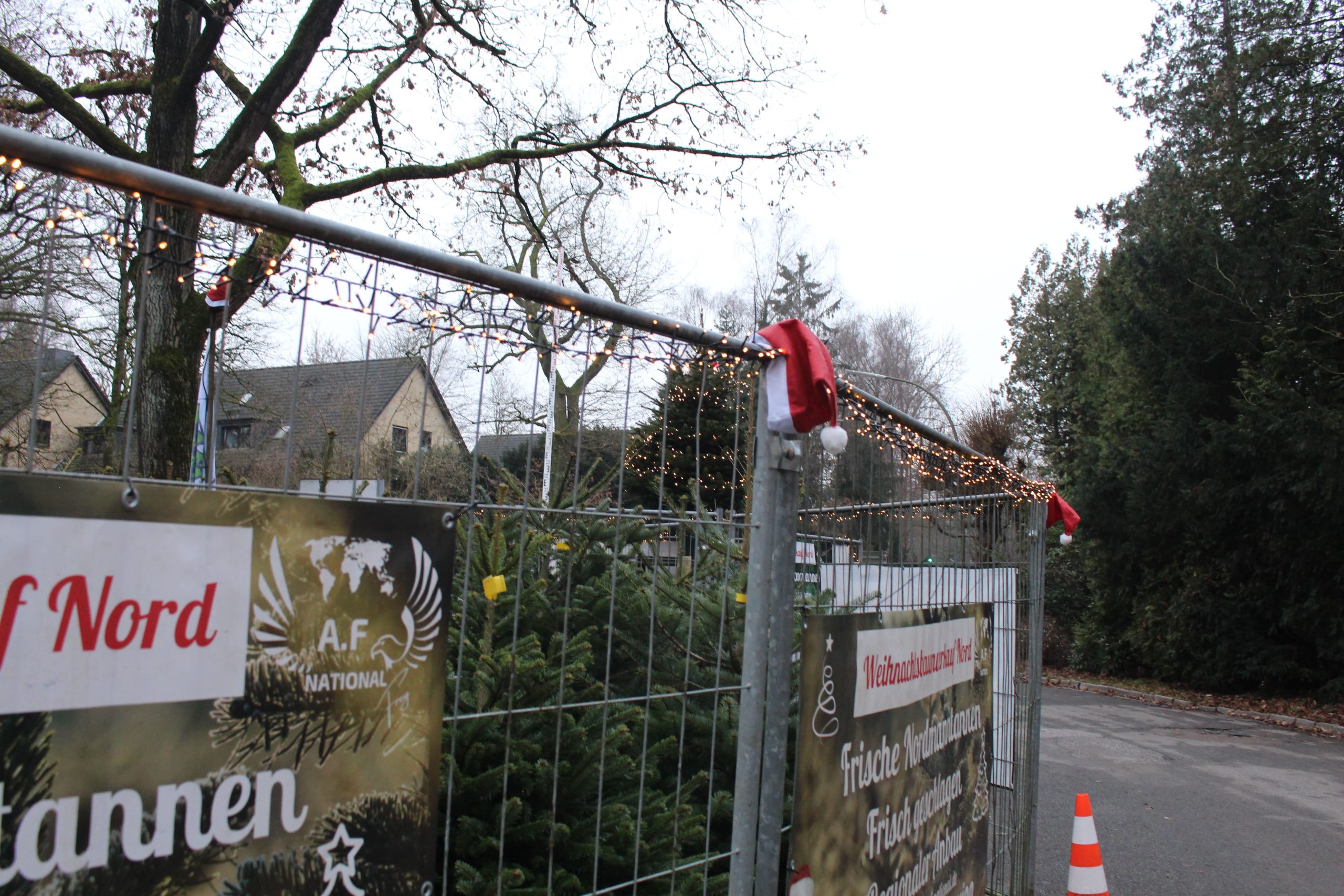 Ein Zaun mit Weihnachtsmützen drauf.