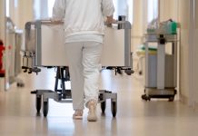 909 Grippe-Kranke 2024 im Krankenhaus behandelt Person schiebt Bett durch Krankenhausflur