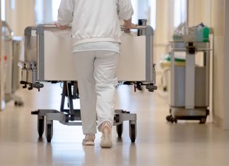 909 Grippe-Kranke 2024 im Krankenhaus behandelt Person schiebt Bett durch Krankenhausflur