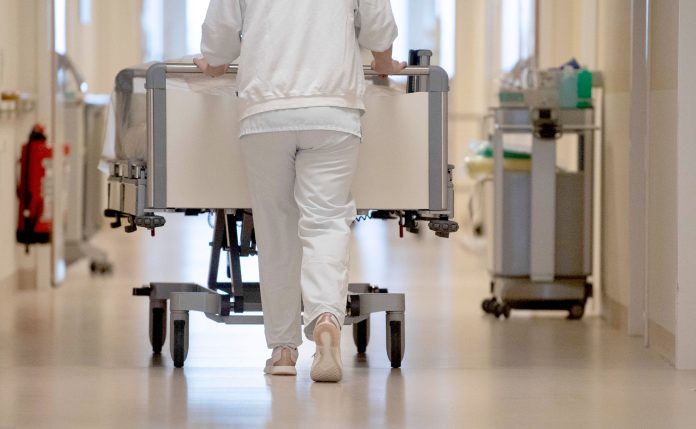 Person schiebt Bett durch Krankenhausflur