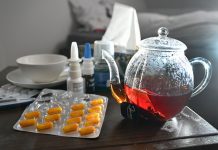 Influenza und Covid-19: Steigende Zahlen in Hamburg Medikamente und eine Kanne und Tasse Tee sind auf einem Nachttisch aufgestellt.