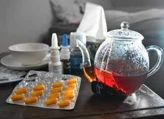 Influenza und Covid-19: Steigende Zahlen in Hamburg Medikamente und eine Kanne und Tasse Tee sind auf einem Nachttisch aufgestellt.