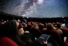 „MindSpace” – Der innere Kosmos Zu sehen sind Personen auf ihren Sitze im Sternensaal des Planetariums. Sie schauen mit 3D-Brillen auf die Projektionsfläche. Auf der Projektionsfläche der Kuppel ist ein Teil eines Universums zu sehen.