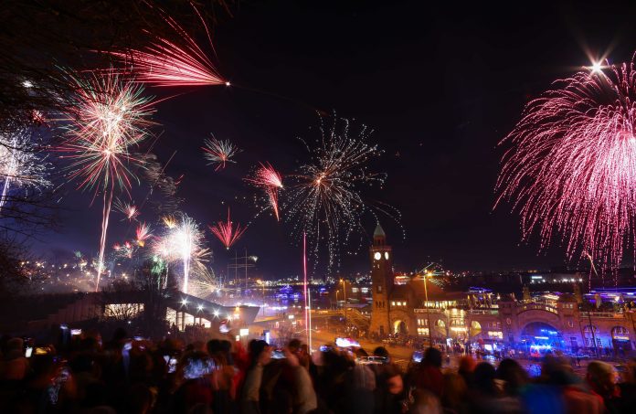 Das Bild zeigt den Hamburger Hafen und eine Menschenmenge. Ein Feuerwerk ist zu sehen.
