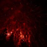 Bunter Himmel, graue Folgen Die roten Lichter einer Rakete sind am dunklen Himmel zu sehen.