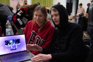 Zwei Personen schauen zeigen ihren Bildschirm auf dem das Gewinnerspiel zu sehen ist.