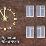 Hamburg hat bundesweit die dritthöchste Arbeitslosenquote Außenansicht auf ein Backsteingebäude mit einer goldenen Uhr und dem roten Logo der Agentur für Arbeit.