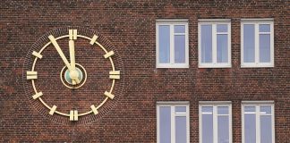 Hamburg hat bundesweit die dritthöchste Arbeitslosenquote Außenansicht auf ein Backsteingebäude mit einer goldenen Uhr und dem roten Logo der Agentur für Arbeit.