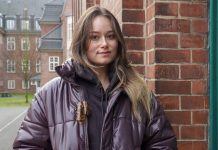 „Ich möchte einfach keine Mutter sein“ Eine junge Frau schaut in die Kamera. Sie hat lange braune Haare und steht vor einer Mauer. Links von ihr ist ein Innenhof im Hintergrund zu erkennen.