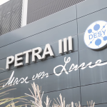 Das DESY forscht an der Zukunft Ein graues Gebäude auf dem Petra III und Max von Laue steht.