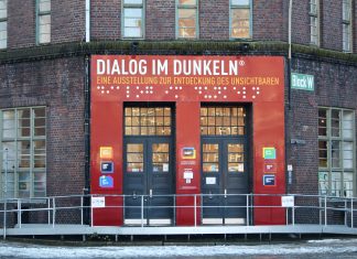 Wie fühlt es sich an, blind zu sein? Der Eingang des Dialoghauses mit dem Schriftzug Dialog im Dunkeln. Darunter nochmal in Blindenschrift. Darunter die Eingangstüren.