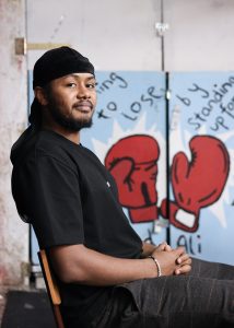 Mohamed sitzt auf einem Stuhl und schaut in die Kamera.