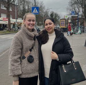 Zwei junge Frauen stehen draußen und lachen für ein Foto.