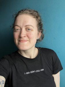 Ein Selfie einer Frau, sie lächelt in die Kamera. Im Hintergrund eine blaue Wand.