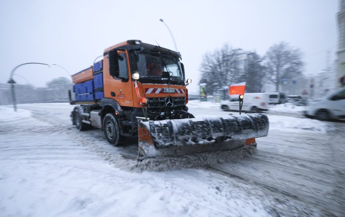 Ein Räum-und Streufahrzeug schiebt Schnee von einer Straße.
