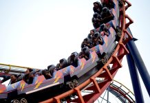 Miniatur-Wunderland plant erste Achterbahn Ausschnitt einer fahrenden Achterbahn mit mehreren Personen, die in den Wagen sitzen.