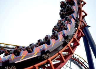 Miniatur-Wunderland plant erste Achterbahn Ausschnitt einer fahrenden Achterbahn mit mehreren Personen, die in den Wagen sitzen.