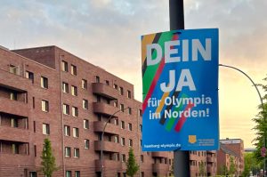 Auf dem Bild sieht man ein Plakat mit der Aufschrift "Dein ja für Olympia im Norden!". Im Hintergrund erkennt man Wohnhäuser.