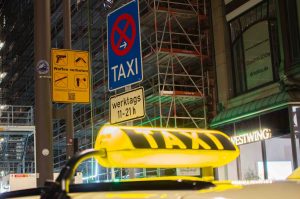 Taxi-Haltestelle am Jungfernstieg. Im Vordergrund ist das gelb leuchtende Schild von Lebastchis Taxi zu sehen.