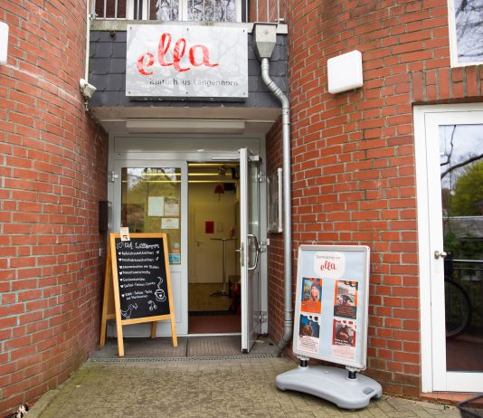 Wo (fast) alles ein zweites Leben bekommt Das Foto zeigt den Eingang zum Café ella. Die Tür steht offen. Das Gebäude ist ein Backsteinhaus. Neben der geöffneten Tür stehen Aufsteller, die Flyer und einen Teil der Speisekarte zeigen.