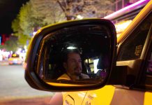 „Beichtvater und Therapeut”: Unterwegs mit einem Taxifahrer Die Spiegelung von dem Taxifahrer Daniel Lebastchi in dem Seitenspiegel seines gelben Taxis. Im Hintergrund ist die Reeperbahn zu erkennen.