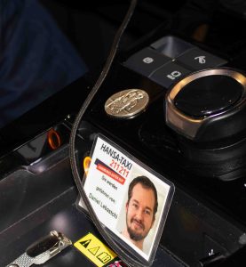 Mittelkonsole des Taxis: Man sieht Knöpfe, die Münze mit dem Schutzpatron der Reisenden, der heilige Christophorus und den Hansa-Taxi-Ausweis von Daniel Lebastchi.