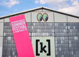 Kampnagel Sommerfestival: Das große Hoffen Die Kulturfabrik Kampnagel in Winterhude mit einem großen pinken Banner, auf dem Sommerfestival in Großbuchstaben steht.
