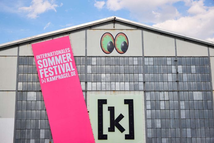 Die Kulturfabrik Kampnagel in Winterhude mit einem großen pinken Banner, auf dem Sommerfestival in Großbuchstaben steht.