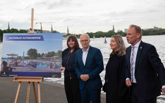 Hamburgs Bürgermeister Dr. Peter Tschentscher, Umweltsenatorin Katharina Fegebank, Sportsenator Andy Grote und Bäderland-Geschäftsführerin Susan Zetzmann stehen an der Außenalster mit einem Bild von einem Entwurf für ein neues Naturbad an der Alster.