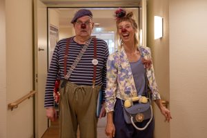 Zwei Clowns stehen im Flur des Pflegeheims Domicil in Billstedt. Sie tragen bunte Klamotten und eine rote Plastiknase.