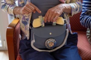 Franziska Heuschkel hat eine blaue Umhängetasche dabei, die aussieht wie ein altes Telefon. Es gibt einen Telefonhörer und eine Drehscheibe.