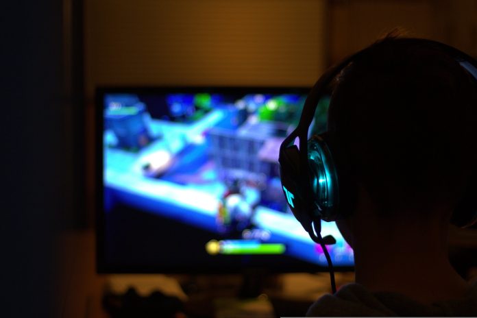 Beim Game-Jam wird entwickelt und gespielt. Foto: pixabay Vor einem bunten Bildschirm sitzt eine Perosn mit Kompfhörern. Beim Game-Jam wird entwickelt und gespielt.