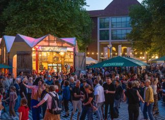 Kostenlos Kultur! Die Altonale startet Das Bild zeigt viele Menschen, die in der Abenddämmerung draußen stehen und tanzen. Im Hintergrund sind bunt beleuchtete Gebäude zu sehen.