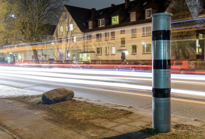 Blitzer Blitzersäule bei Nacht an einer befahrenen Straße. Ein Symbolbild