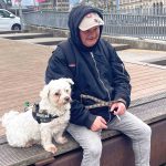 Früher obdachlos, heute Stadtführer Chris sitzt mit seinem Hund Struppi auf einer Bank. Zwischen seinen Fingern hält er eine Zigarette.