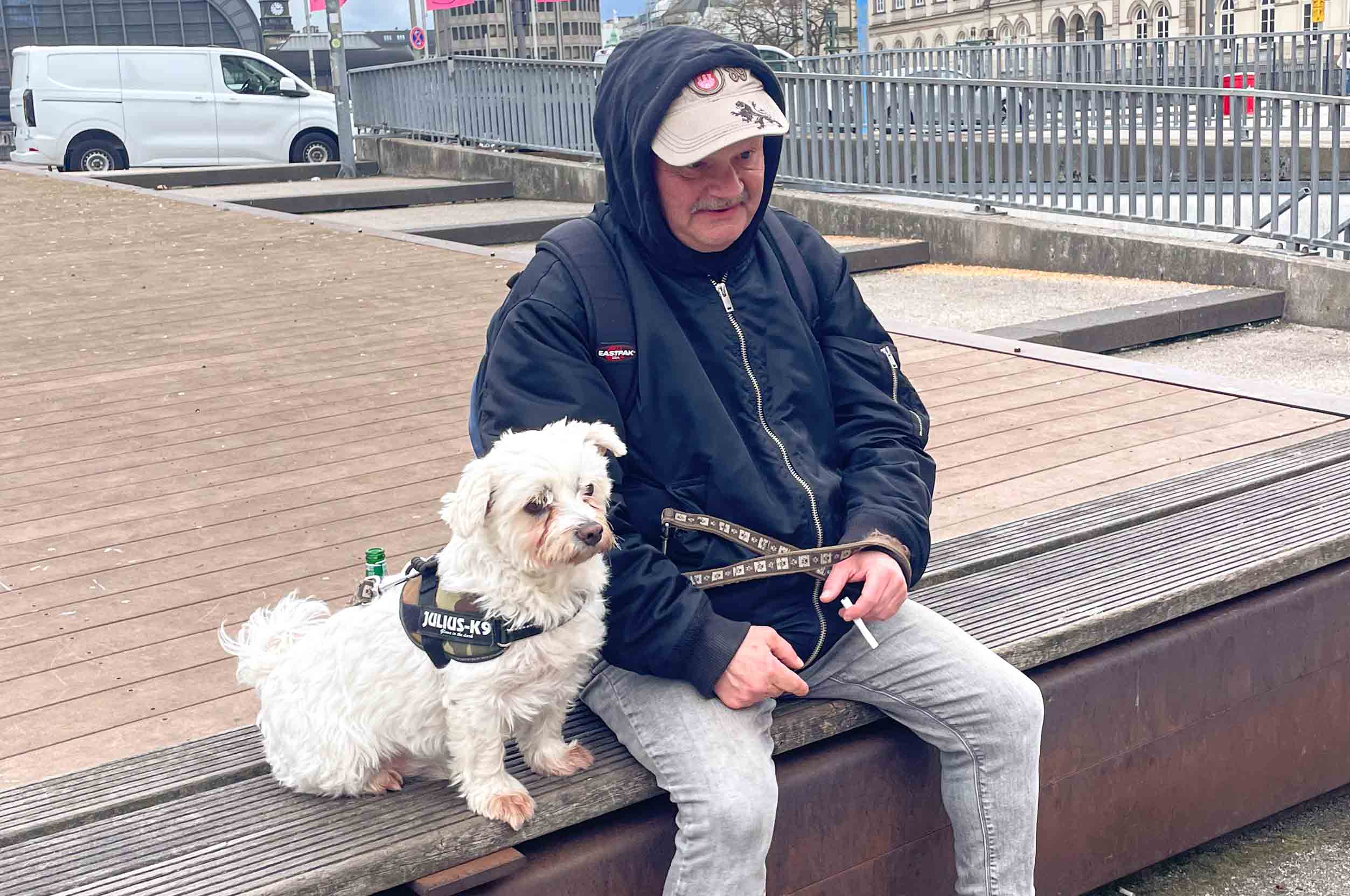 Chris 2 Chris sitzt mit seinem Hund Struppi auf einer Bank. Zwischen seinen Fingern hält er eine Zigarette.