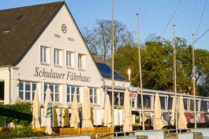 Die Terrasse des Schulauer Fährhauses im warmen Abendlicht mit eingeklappten Sonnenschirmen.