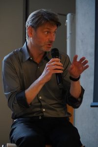 Journalist und Rechtsexperte Andreas Speit bei einer Podiumsdisskusion. Er trägt ein Mikro in der Hand
