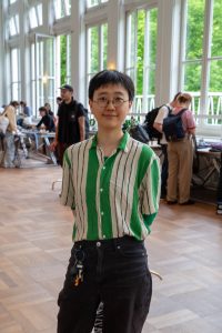 Daha Yeo von den Students for Future steht im Vordergrund. Im Hintergrund sieht man die Kleidertauschparty.
