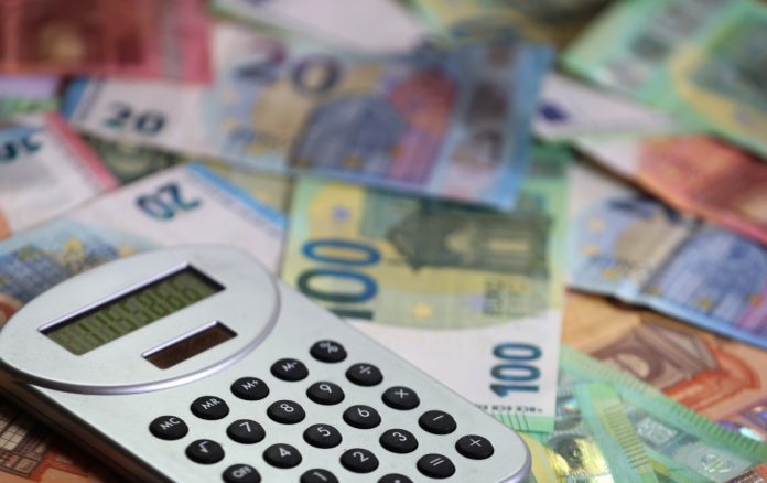 Ein Taschenrechner liegt auf verschiedenen Euro-Banknoten.
