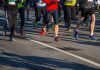 Halbmarathon wegen Hitze abgesagt Mehrere Menschen laufen bei einem Marathon über eine Asphalt-Straße. Das Bild ist oben abgeschnitten, sodass man nur die untere Häkfte der Menschen sieht. Sie tragen Sportkleidung und haben teilweise Schilder mit Zahlen auf ihren T-Shirts.