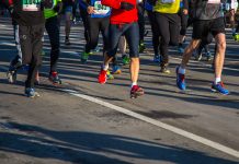 Halbmarathon wegen Hitze abgesagt Mehrere Menschen laufen bei einem Marathon über eine Asphalt-Straße. Das Bild ist oben abgeschnitten, sodass man nur die untere Häkfte der Menschen sieht. Sie tragen Sportkleidung und haben teilweise Schilder mit Zahlen auf ihren T-Shirts.