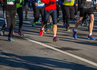 Halbmarathon wegen Hitze abgesagt Mehrere Menschen laufen bei einem Marathon über eine Asphalt-Straße. Das Bild ist oben abgeschnitten, sodass man nur die untere Häkfte der Menschen sieht. Sie tragen Sportkleidung und haben teilweise Schilder mit Zahlen auf ihren T-Shirts.