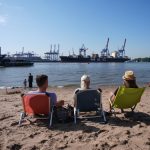Hamburg, der Sommer ist da! Personen sitzen auf Liegestühlen am Elbstrand.