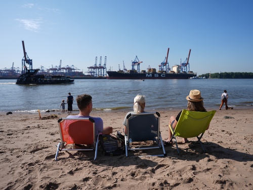 Sommerwetter - Hamburg Personen sitzen auf Liegestühlen am Elbstrand.