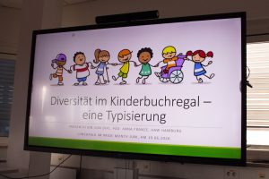 Das Bild zeigt einen Bildschirm auf dem eine Präsentation gezeigt wird. Dort steht: Diversität im Kinderbuchregal – eine Typisierung.