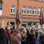 „Altona macht auf“: Tanz auf dem Balkon Eine Menschentraube steht im Hof der Zeisehallen und schaut zu einer Frau, die durch ein Megafon spricht.