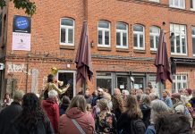„Altona macht auf“: Tanz auf dem Balkon Eine Menschentraube steht im Hof der Zeisehallen und schaut zu einer Frau, die durch ein Megafon spricht.